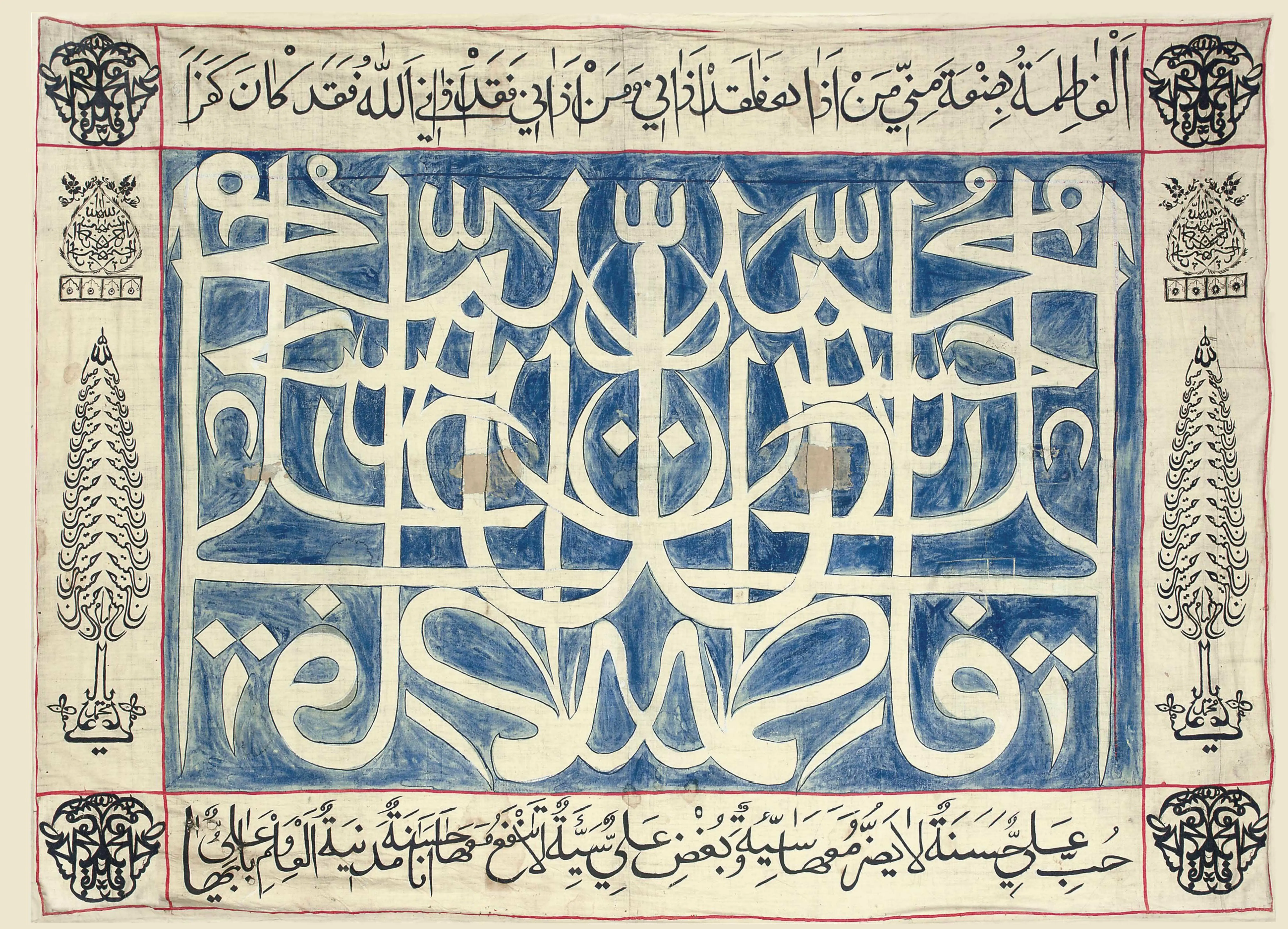 A rectangular cloth panel of Arabic calligraphy: at the centre, large interlaced white letters on a blue ground form the names of the Prophet Muhammad, Ali, Fatimah, Hasan and Hussain; bands of black script run along the top and bottom, and the borders carry mirrored black calligraphic devices in the corners and tall cypress-shaped designs at the sides