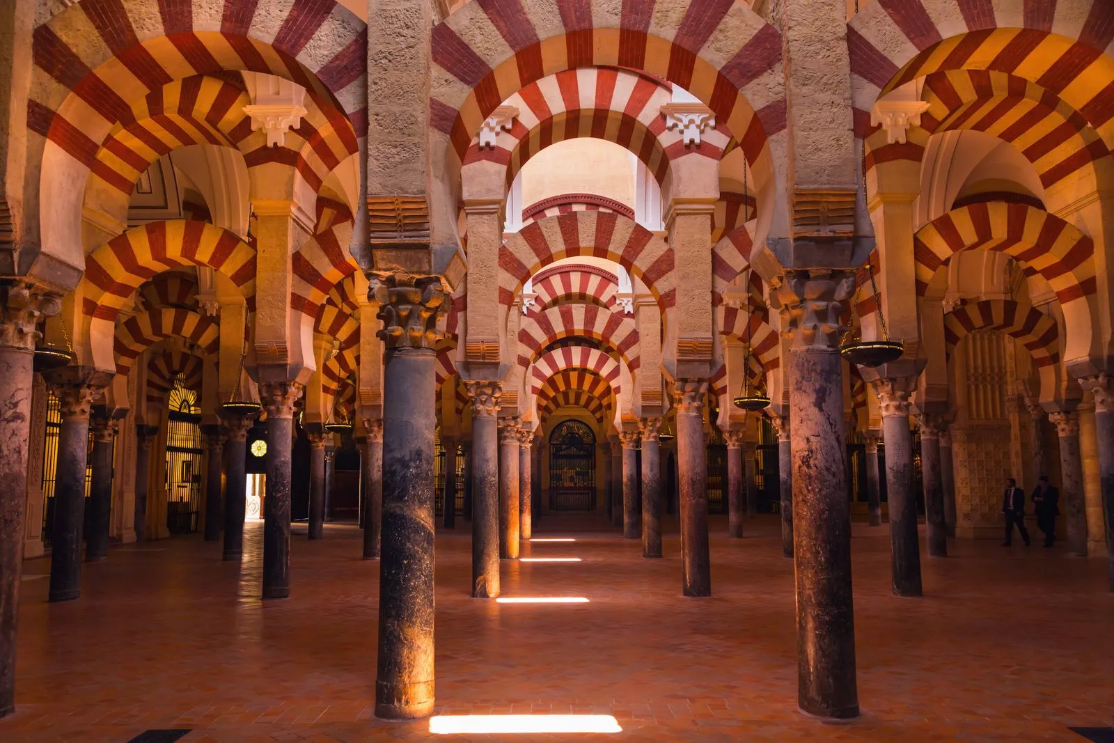 Interior of the Mosque of Cordoba, rows of columns supporting double-tiered arches striped in red and white receding into the distance